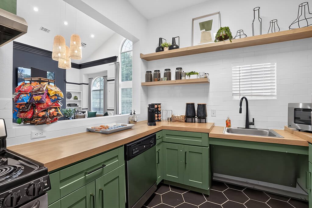 A kitchen with green cabinets and a wooden counter.